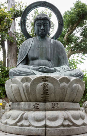 Kyoto, Japan - September 15, 2016: At the Shinnyo-do Buddhist Temple the stone statue of the meditating or Amithabha Buddha stands in the garden. He sits on lotus and has big halo.のeditorial素材