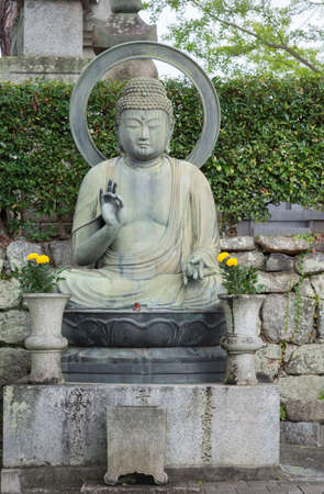 Kyoto, Japan - September 15, 2016: Kurodani Buddhist Temple displays Buddha statue in teaching and protecting pose. Big halo, and green hedge as background.のeditorial素材