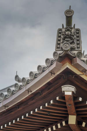 Kyoto, Japan - September 16, 2016: Crest of wooden roof structure at Chion-in Buddhist Temple under cloudy sky. Gray emblem and roof tiles.のeditorial素材