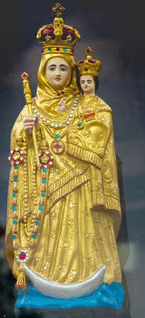 Vadipatti, India - October 22, 2013: Closeup of golden Virgin Mary statue at Vadipatti Arockia Annai Shrine. She holds baby jesus. Both wear a crown. Slim crescent moon present. Plenty of jewels.のeditorial素材