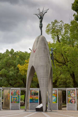 Hiroshima, Japan - September 20, 2016: Memorial statue for the children who died during and after the A-bomb explosion. Young girl holds origami crane figure above her head. Park setting.のeditorial素材