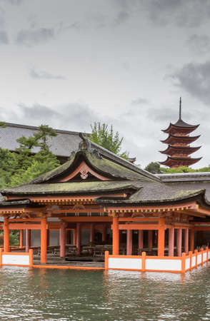 Hiroshima, Japan - September 20, 2016: Vermilion part of itsukushima Shinto Shrine on Miyajima Island built barely above sea level. Pagoda of Hokokujinjahonden Shrine in background.のeditorial素材