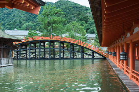 Hiroshima, Japan - September 20, 2016: Bridge and vermilion halls at itsukushima Shinto Shrine on Miyajima Island. Row of lanterns. Construction barely above sea level.のeditorial素材