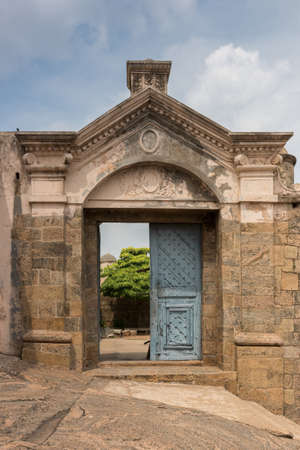 Dindigul, India - October 23, 2013: Gate construction with blue doors as entrance to the historic Dindigul Rock fort under light blue sky. Brown-beige as dominant color.のeditorial素材