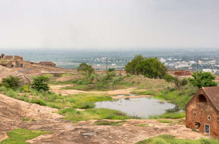 Dindigul, India - October 23, 2013: Rain water is collected in a couple of ponds inside the historic Dindigul Rock fort. View over wall onto surrounded region. Green environment around lake.のeditorial素材
