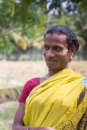 Dindigul, India - October 23, 2013: Smiling Hijra transgender person in a rural setting wears a beautiful yellow sari with maroon T-shirt. Her name is Sandra.のeditorial素材