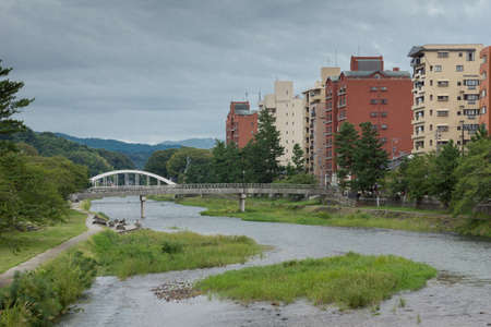 Kanazawa, Japan - September 22, 2016: The Asanogawa River flows through downtown. Green borders and islands. Modern apartment housing on one side.のeditorial素材