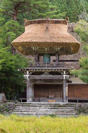 Shirakawago, Japan - September 23, 2016: Even the bell tower of the Myozenji Buddhist temple in Shirakawago had the particular joined-hands roof. Green foliage and yellow rice paddy.のeditorial素材