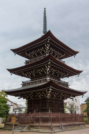 Takayama, Japan - September 24, 2016: Three story Pagoda at Hikakokubun-ji Buddhist Temple has dark wood structure and long bronze top under light blue sky.のeditorial素材