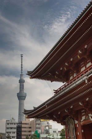 Tokyo, Japan - September 26, 2016: Part of vermilion roof of Hozomon Gate at Senso-ji Buddhist Temple with tall Skytree tower in the distance under blue cloudy sky.のeditorial素材