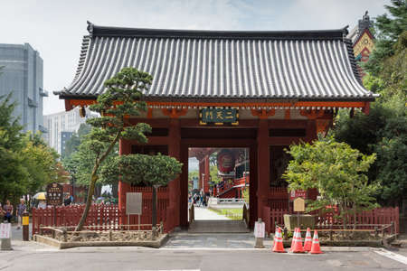 Tokyo, Japan - September 26, 2016: The vermilion Nitenmon Gate of Senso-ji Buddhist Temple in Tokyo. Eastern Entrance. People and part of Honzo hall visible. Light blue sky some green foliage.のeditorial素材