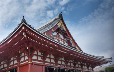 Tokyo, Japan - September 26, 2016: Part of the highly decorated vermilion roof of the Honzo main hall at Senso-ji Buddhist Temple under blue cloudy sky. Gold metalic decorations.のeditorial素材