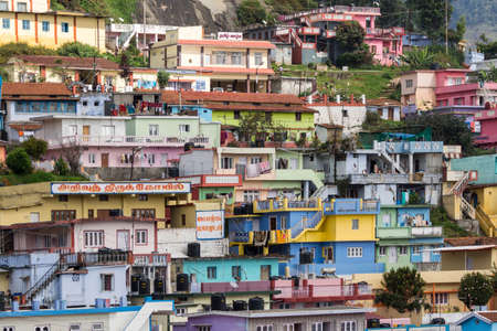 Ooty, India - October 25, 2013: Colorful collection of houses built close together above each other on a slope near Wellington Contonment along road 181. People,  cars, laundry, business.のeditorial素材