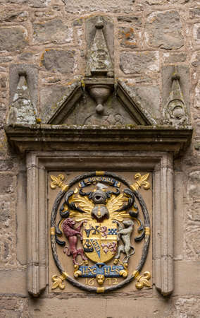 Cowdor, Scotland - June 2, 2012: Gold, red and blue coat of arms with slogan Be Mindful. Set in a...