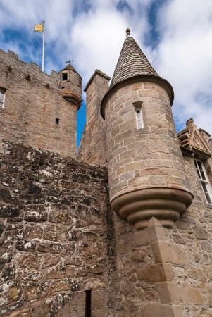 Cowdor, Scotland - June 2, 2012: Closeup of the brown-gray stone structure of gate and watchtower of undamaged Cowdor Castle. Flag on top.のeditorial素材