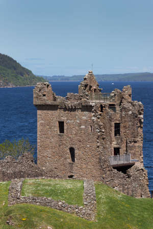Loch Ness, Scotland - June 2, 2012: The ruins of the main tower and house of Urquhart Castle sit on a cliff looking over deep blue Loch Ness. Surrounding green hills. Light blue sky.のeditorial素材
