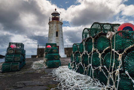 Lybster, Scotland - June 4, 2012: Green lobster traps are stacked on black stone pier of Lybster...