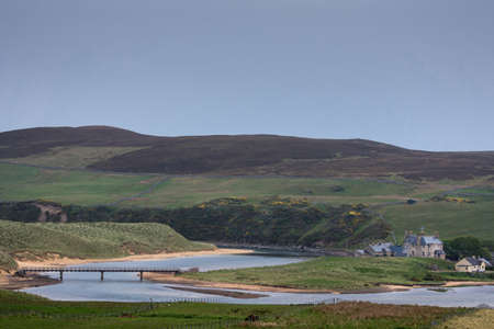North Coast, Scotland - June 6, 2012: Meandering Halladale River with bridge. Mansion is built in green environment in the bend of the blue river. Open sky and brown hills on horizon.のeditorial素材