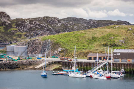Northwest Coast, Scotland - June 6, 2012: The pleasure vessel section of Scourie harbor shows the docks, a dozen boats on the ocean water. Against gray rocky hills with green pasture patches.のeditorial素材