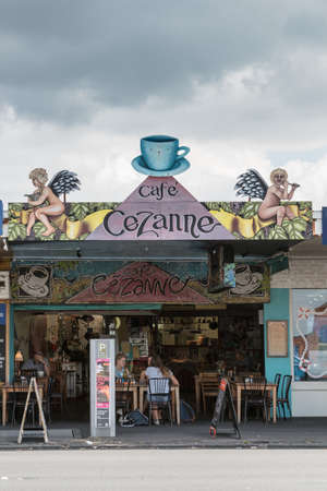 Auckland, New Zealand - March 1, 2017: Colorful facade of Cezanne coffee shop on Ponsonby Road features angles and coffee related symbols under cloudy sky. Patrons sitting at tables.のeditorial素材