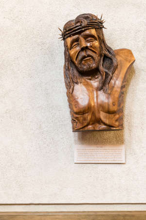 Auckland, New Zealand - March 4, 2017: The Tear, brown wooden sculpture hangs in Holy Trinity Cathedral celebrating organ transplant donors and recipients. White beig wall. Face of crying Christ with thorn crown.のeditorial素材