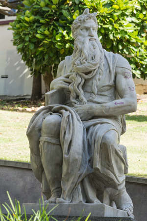 Auckland, New Zealand - March 5, 2017: Closeup of gray marble Moses statue by Michelangelo in Myers Park. Green vegetation background. Some graffiti as tattoos on his arm.のeditorial素材