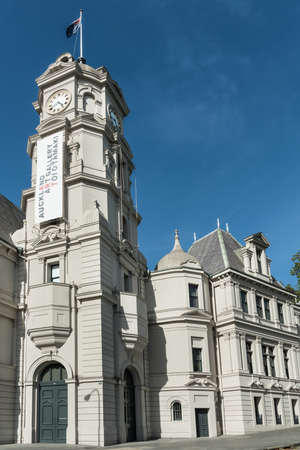 Auckland, New Zealand - March 5, 2017: Closeup of the gray stone clock tower and building of public Auckland Art Gallery set along the street. Blue sky.のeditorial素材