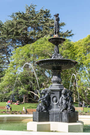 Auckland, New Zealand - March 5, 2017: Closeup of Black metal 19th century Victorian Fountain in center of Albert Park. Green vegetation, people in back under blue sky.のeditorial素材