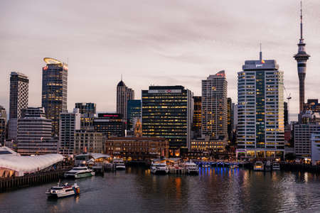 Auckland, New Zealand - March 6, 2017: Ferry building in front of HSBC office building with Sky Tower and a few more high rises in background at sunset. Ferries at docks.のeditorial素材