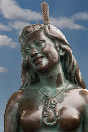 Napier, New Zealand - March 9, 2017: Closeup of the face of the iconic Maori symbol, Pania of the Reef. Bronze statue in the beach park against blue sky with a few white clouds.のeditorial素材