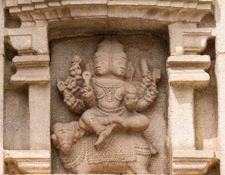 Nanjangud, India - October 26, 2013: Closeup of chiseled mural of multi-headed God Agni sitting on a bull in beige sandstone of the Mandapam at Srikanteshwara Temple.のeditorial素材
