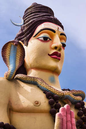 Nanjangud, India - October 26, 2013: Closeup of chest of giant Lord shiva statue off Srikanteshwara Temple against blue sky. Multicolor and with cobra snake, named Vasuki.のeditorial素材