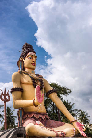 Nanjangud, India - October 26, 2013: Isolated giant Lord shiva statue off Srikanteshwara Temple against blue sky with white clouds. Multicolor and with cobra snake, named Vasuki.のeditorial素材