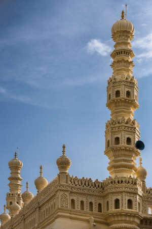 Mysore, India - October 26, 2013: Cream yellow minaret and part of upper structure of mosque at Tipu Sultan mausoleum under blue sky. Sound system.のeditorial素材