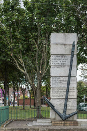 Dublin, Ireland - August 7, 2017: Gray stone War Memorial in honor of the seamen lost while serving on Irish Merchant ships between 1939-1945 under green trees. Street scene.のeditorial素材