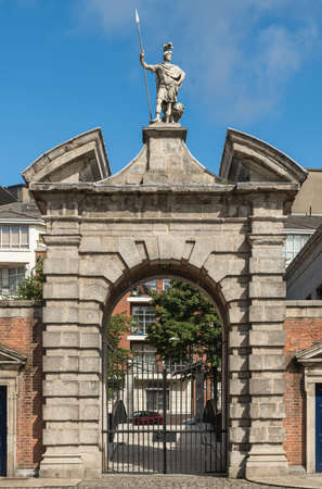 Dublin, Ireland - August 7, 2017: Monumental beige stone entrance gate  to central square of Castle. Statue of Roman guard and lion on top. Closed with view on outside street. Blue sky.のeditorial素材