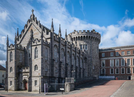 Dublin, Ireland - August 7, 2017: Original church and tower of The Castle, build with dark gray stones, under blue sky with white clouds. Newer side building in back.のeditorial素材
