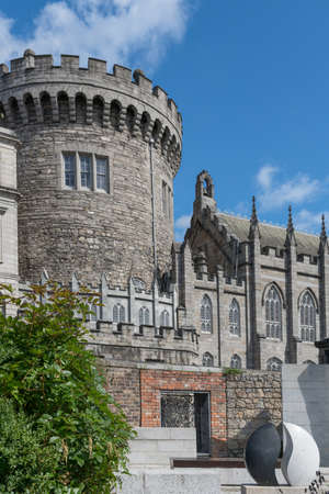 Dublin, Ireland - August 7, 2017: Thick central gray stone watch tower of The Castle under clear blue sky. Part of castle church on the side. All seen from adjacent Dubh-linn garden.のeditorial素材