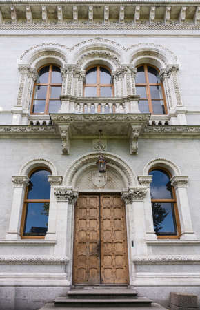 Dublin, Ireland - August 7, 2017: Monumental Entrance to Freeman Library of Geography shows wooden double door, balcony, five windows with decorated frames on beige stone wall.のeditorial素材