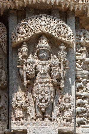 Mysore, India - October 27, 2013: Closeup of brown stone, well preserved Lord Vishnu in full regalia statue on outside wall of Trikuta shrine.のeditorial素材
