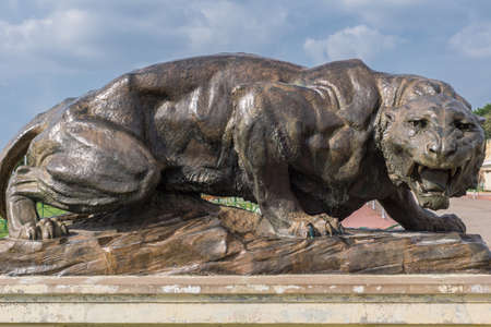 Mysore, India - October 27, 2013: Closeup of dark brown bronze statue of aggressive lioness in front garden of Mysore Palace under cloudscape.のeditorial素材