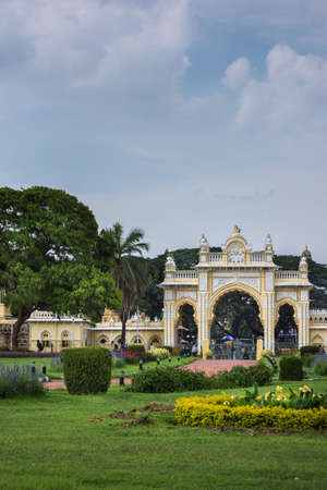 Mysore, India - October 27, 2013: Green garden with flowers in front of closed North Gate to Mysore Palace under cloudscape.のeditorial素材