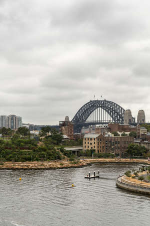 Sydney, Australia - March 21, 2017: Sydney Harbour bridge under gray rainy sky behind green Barangaroo Reserve and Munns Slipway. Barangaroo skyline and bay water in front.のeditorial素材