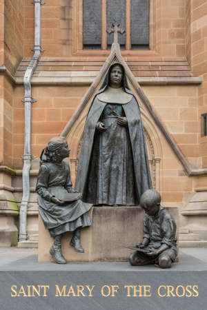 Sydney, Australia - March 23, 2017: Balck bronze statue of nun with two children named Saint Mary of the Cross on side of brown facade of Saint Marys Cathedral. Ms. Mckillop was the first saint of Australia.のeditorial素材