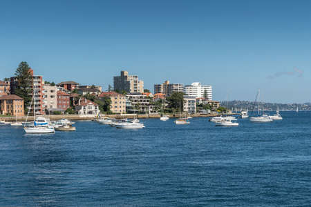 Sydney, Australia - March 26, 2017: Plenty of mostly white yachts on blue water of North Harbour in front of Manly boardwalk close to Smedley Point. Clear blue sky and condominiums on shore.のeditorial素材