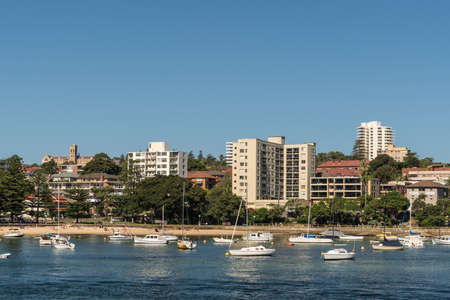 Sydney, Australia - March 26, 2017: Plenty of mostly white yachts on blue water of North Harbour in front of Manly boardwalk at Cabbage Tree Bay and beach. Clear blue sky and condominiums on shore.のeditorial素材