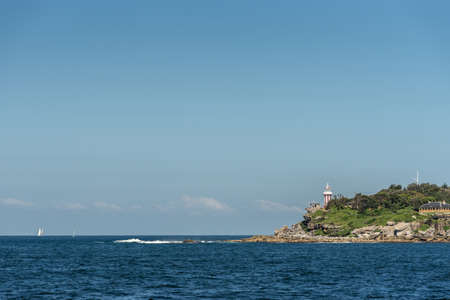 Sydney, Australia - March 26, 2017: South Head clliffs with Hornby lighthouse at entrance to the bay from Tasman Sea under open blue sky and dark blue sea water. Some yachts in distance.のeditorial素材