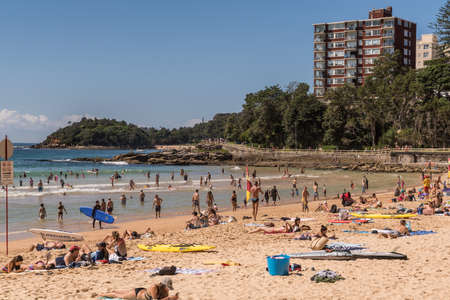 Sydney, Australia - March 26, 2017: Section of Manly Beach with sand and Tasman Sea. People on the sand and in the water. Condominium tower and green belt.のeditorial素材