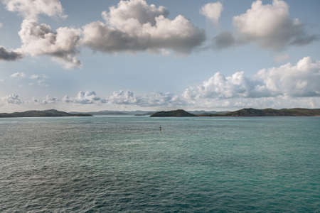 Barrier Reef, Australia - December 3, 2009: brown islands stick out of a azure blue water under a white and gray prominent cloudscape in light blue sky in the Coral Sea.のeditorial素材