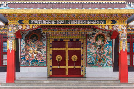 Coorg, India - October 29, 2013: Main entrance door Zangdog Palri temple at Namdroling Buddhist Monastery. Colorful Dwaralapakas painting as warrior and musician. Golden Beam artwork.のeditorial素材
